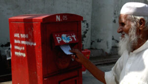 old bearded man dropping a letter into the mailbox